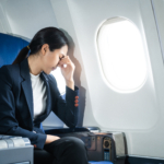 A woman in a formal suit sits in a window seat of an economy cla