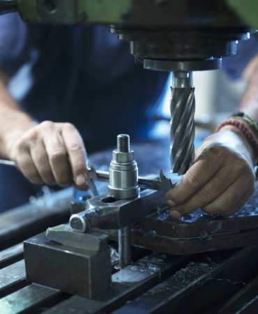 Worker operating industrial machine in metal workshop.